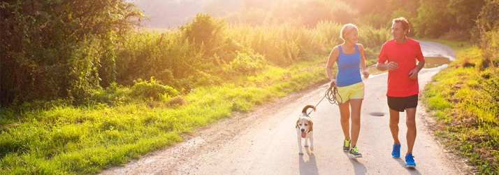 Active couple running on road with dog